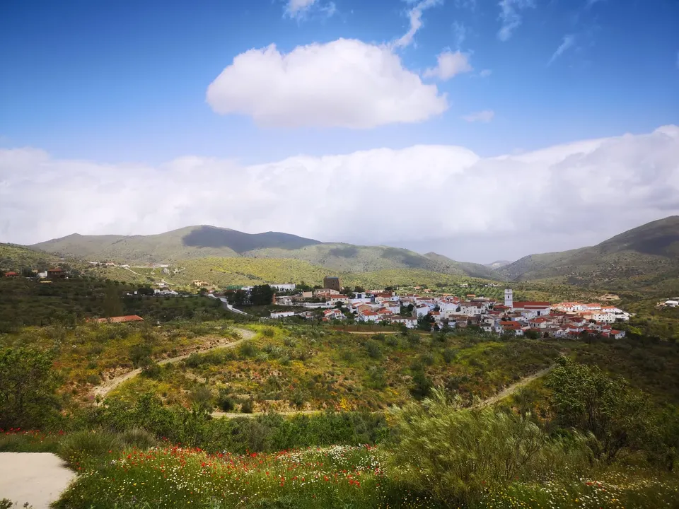 El caserío de Fondón en el fondo del valle, rodeado de lomas verdes y bajo un cielo de nubes altas